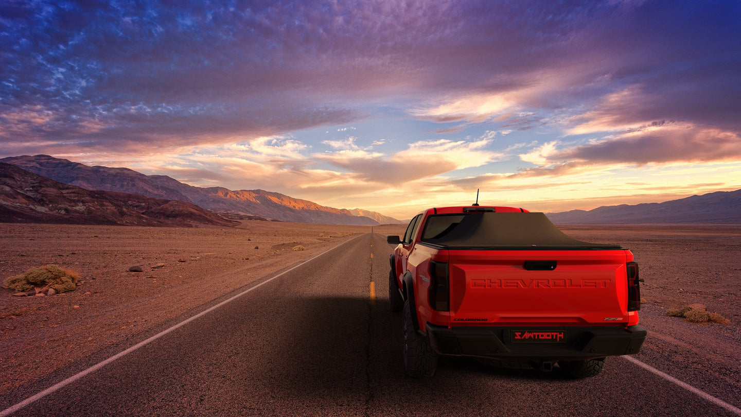 Red Chevrolet Colorado / GMC Canyon with Sawtooth Stretch tonneauexpanded over tall caro on a desert road